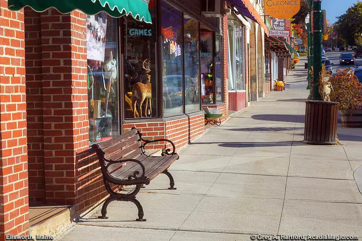 A bench on sidewalk next to Main Street in Ellsworth, Maine